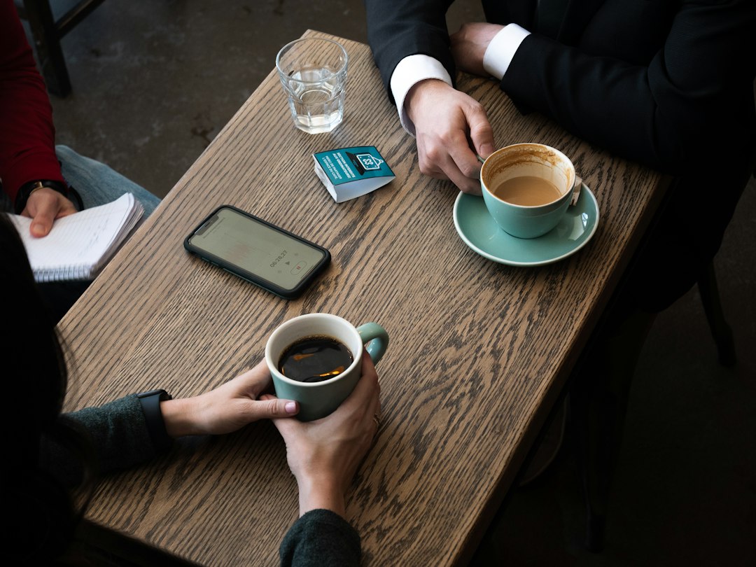 Two people sitting at a table over cups of coffee, talking calmly