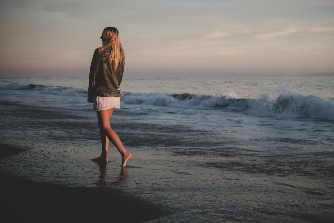 Person taking a quiet, reflective stroll along the shore in warm low sunlight