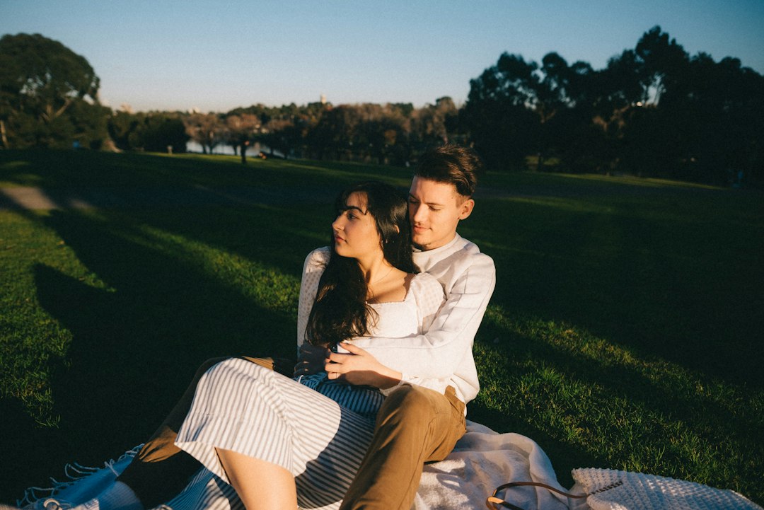 Couple sitting relaxed together on a picnic blanket in warm evening light
