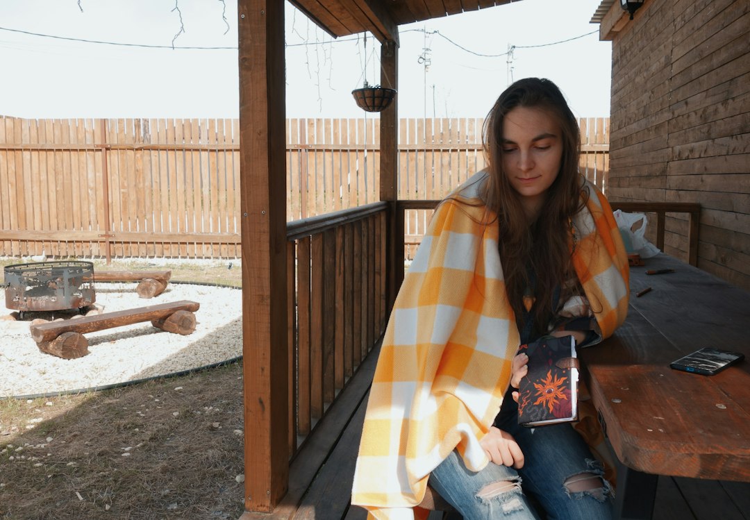Woman sitting contentedly on her porch with a book, enjoying her own space