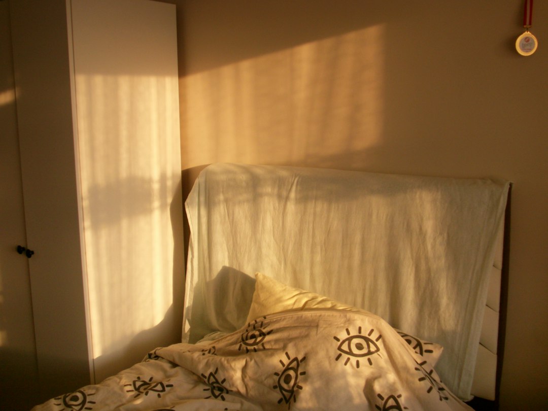 Warm morning sunlight streaming into a calm bedroom across a soft, inviting bed